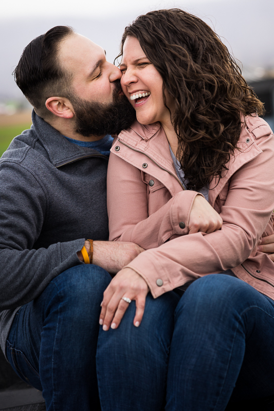 colorful image of the couple kissing and laughing during their rainy engagement session in maryland