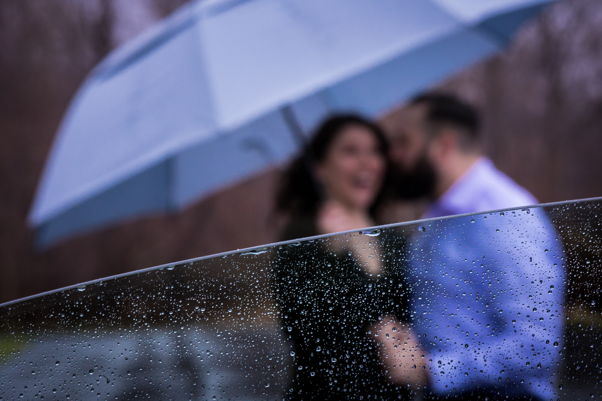 creative unqiue image from this Rainy Pen Mar Engagement of the couple standing outside the window of the car with the raindrops on the windows in focus