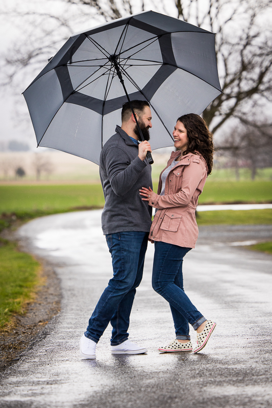 candid photo of the couple laughing and smiling as they stand in the walkway during their Rainy Pen Mar Engagement