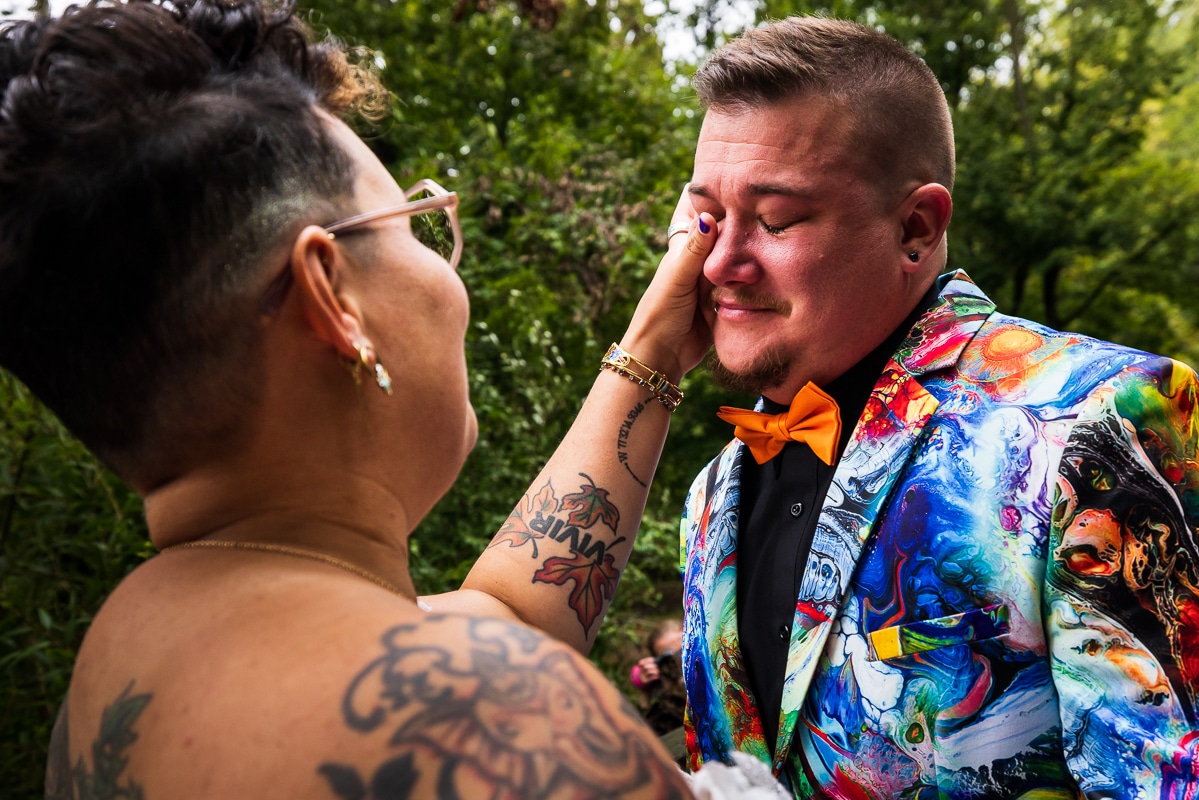 LGBTQIA+ Wedding Photographer, Lisa Rhinehart, captured a colorful, vibrant image of the couple during their first look wiping away eachother's tears during their backyard Pennsylvania wedding