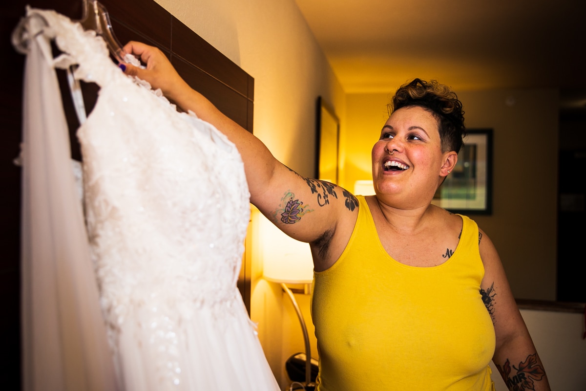 unique image from this backyard wedding during their preparations getting their colorful wedding dress off the hanger