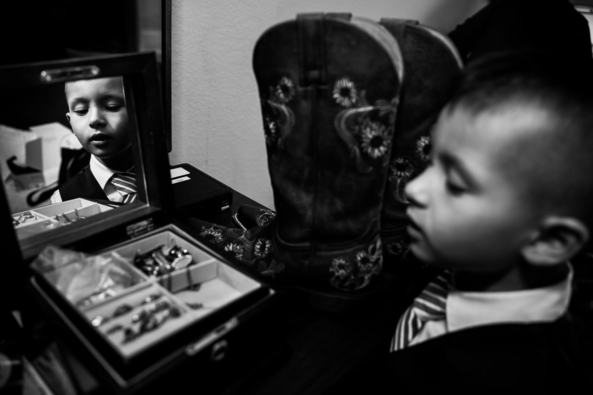 unique creative black and white image of a young boy looking into a jewelry box with boots behind him during these Waynesboro Pennsylvania wedding preparations