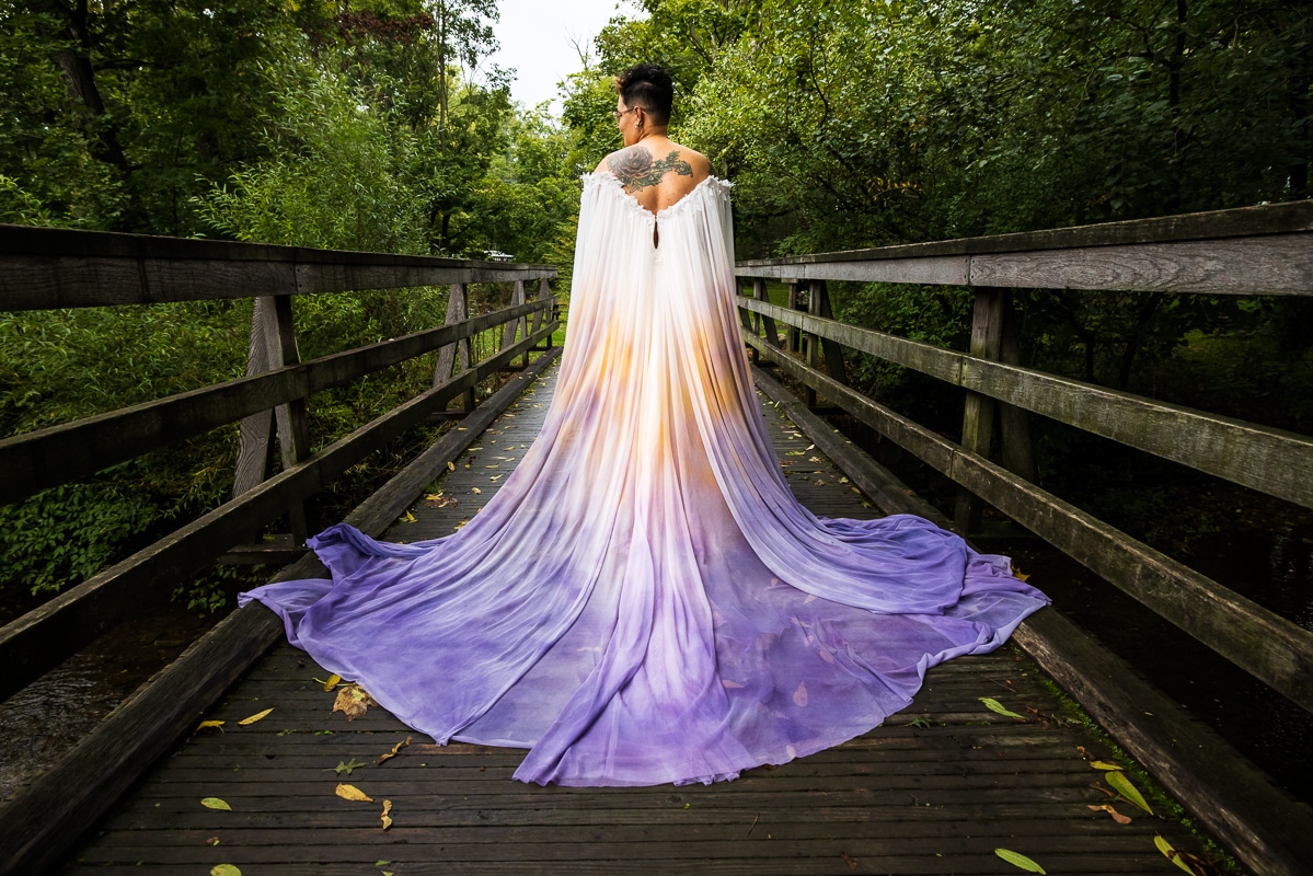 LGBTQIA+ Wedding Photographer, Lisa Rhinehart captured a vibrant, colorful image of a unique and colorful purple, orange and white dress on a bridge at Renfrew Park in Waynesboro, PA