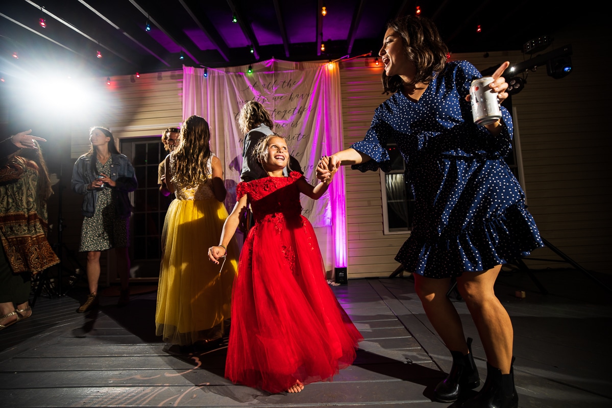 Colorful image of guests in red, yellow, blue, green, pink dresses dancing on the families deck during their backyard wedding in waynesboro pa