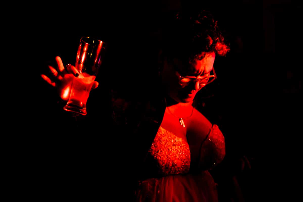 unique, dramatic red lit image of the bride holding a glass and dancing during their wedding reception in their backyard in waynesboro, pa