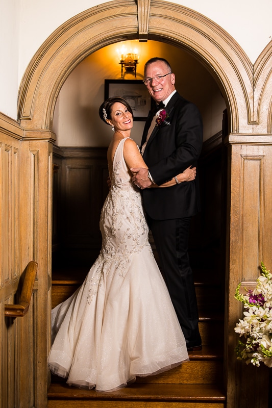 Traditional portrait of the bride and groom standing in a wooden door arch way smiling at the camera hugging on another after their civic club of Harrisburg wedding 