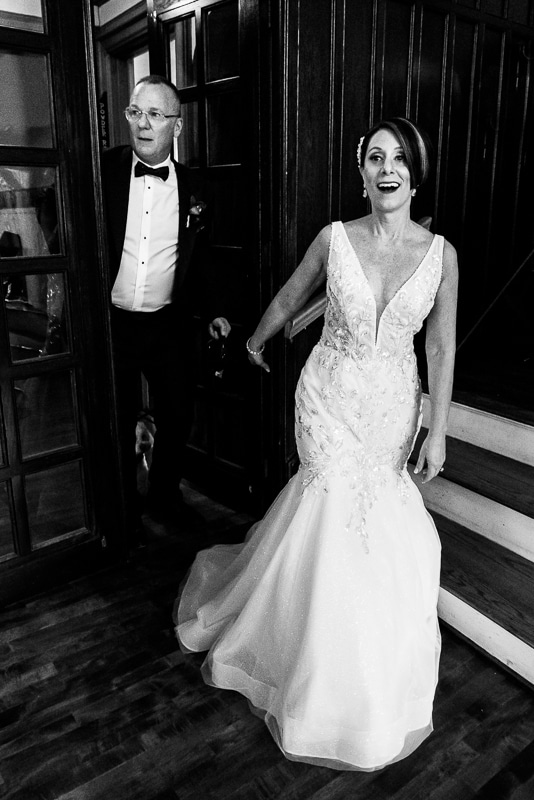 Black and white image of the bride and groom walking in to see their wedding reception venue all set up 