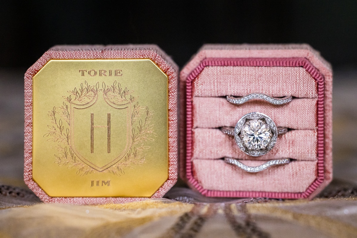 Detail photo of the bride's rings which are in a pink and gold box with her name on it