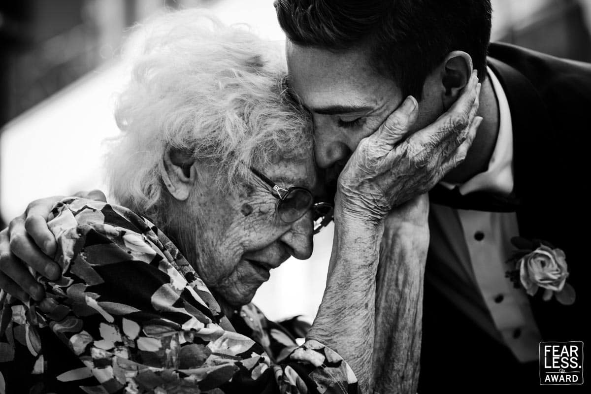 Rhinehart Photography captures this fearless photographer winner is a black and white image of a grandma holding the groom's face in her hands