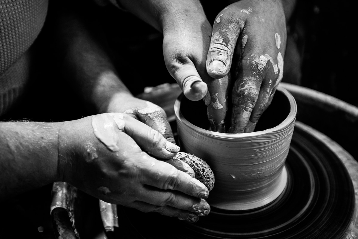 Creative Engagement Photographer, lisa rhinehart, captures a black and white image of the couple with their hands covered in clay as they make pottery together during their engagement session in central pa 