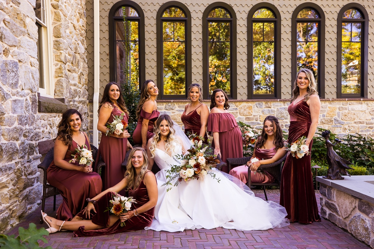 colorful unique image of the bride and her bridesmaids for a group shot outside of the mansion in their maroon dresses 