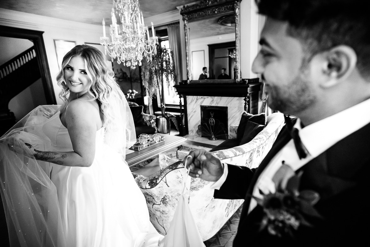 Black and white image of the bride smiling back at the groom as her holds her dress up and smiles at her before their wedding ceremony in mechanicsburg pa 