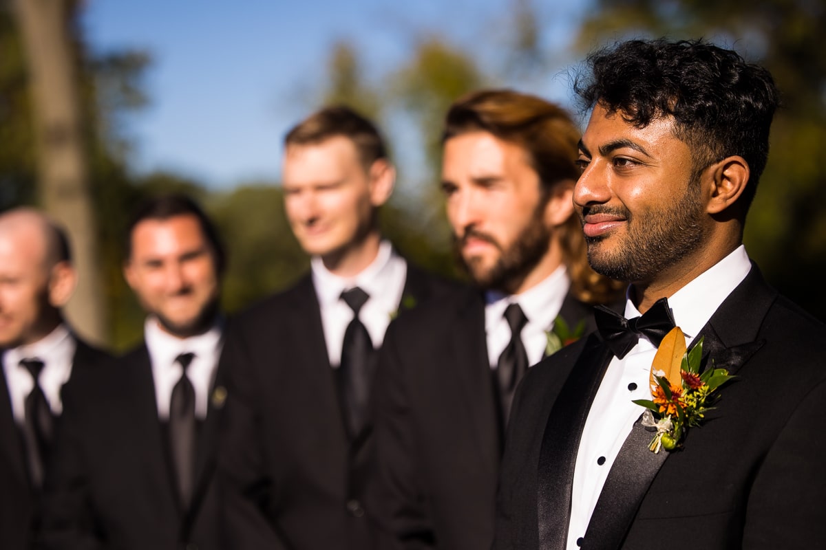 ashcombe mansion photographer, lisa rhinehart, captures the groom looking down the aisle smiling at the bride as she walks down 