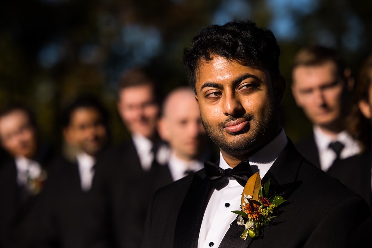 image of the groom looking sideways and half smiling with all of his groomsmen standing behind him during their wedding ceremony in mechanicsbrg pa 