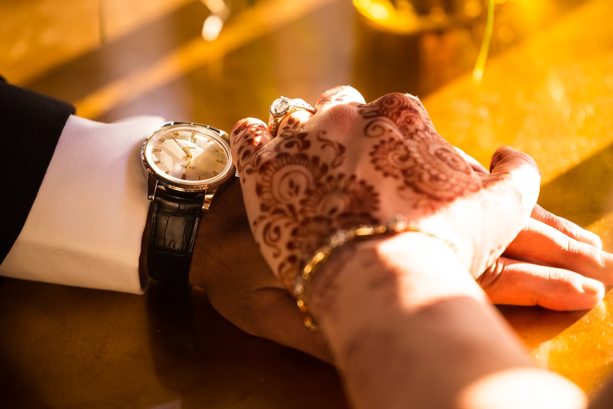 Willows at Ashcombe photographer, lisa rhinehart, captures a close up of couple holding hands in the golden hour sunlight. the brides hand is decorated in brown henna 