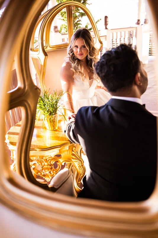 creative, unique image of the bride smiling at the groom which is captured through the back of a unique chair after their wedding ceremony 