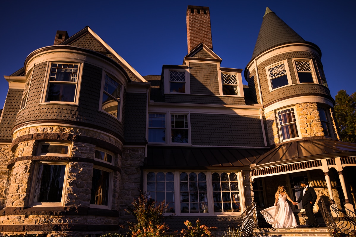 Unique image of the bride and groom holding hands on the porch of the Willows at Ashcombe Mansion in Mechanicsburg, PA after their wedding ceremony 