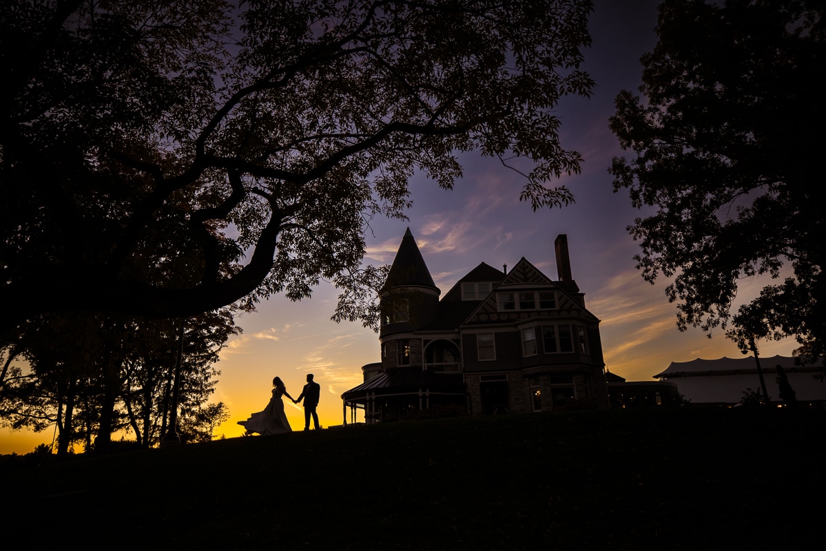 Ashcombe Mansion Wedding photographer, lisa rhinehart, captures this unique and vibrant yellow and purple sunset photo with the couple, the mansion, and the trees silhouetted 
