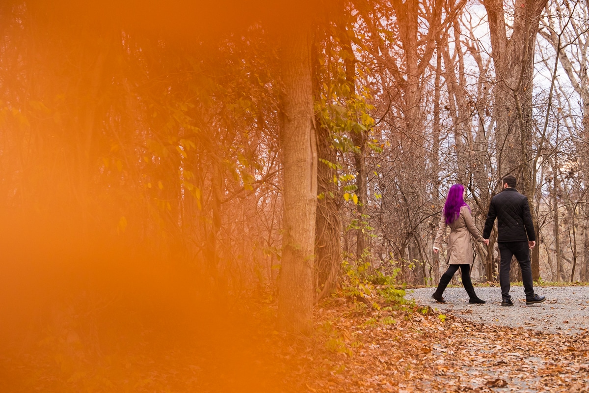 Colorful, vibrant, unique image of the couple walking outdoors holding hands with a bright pop of orange taking over the rest of the image during this Murray Hill Engagement