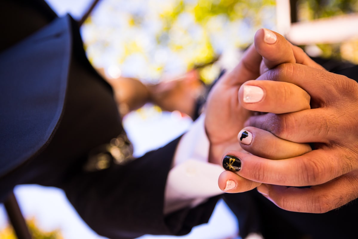 Unique close up image of the couple holding hands and the focus on their unique painted nails
