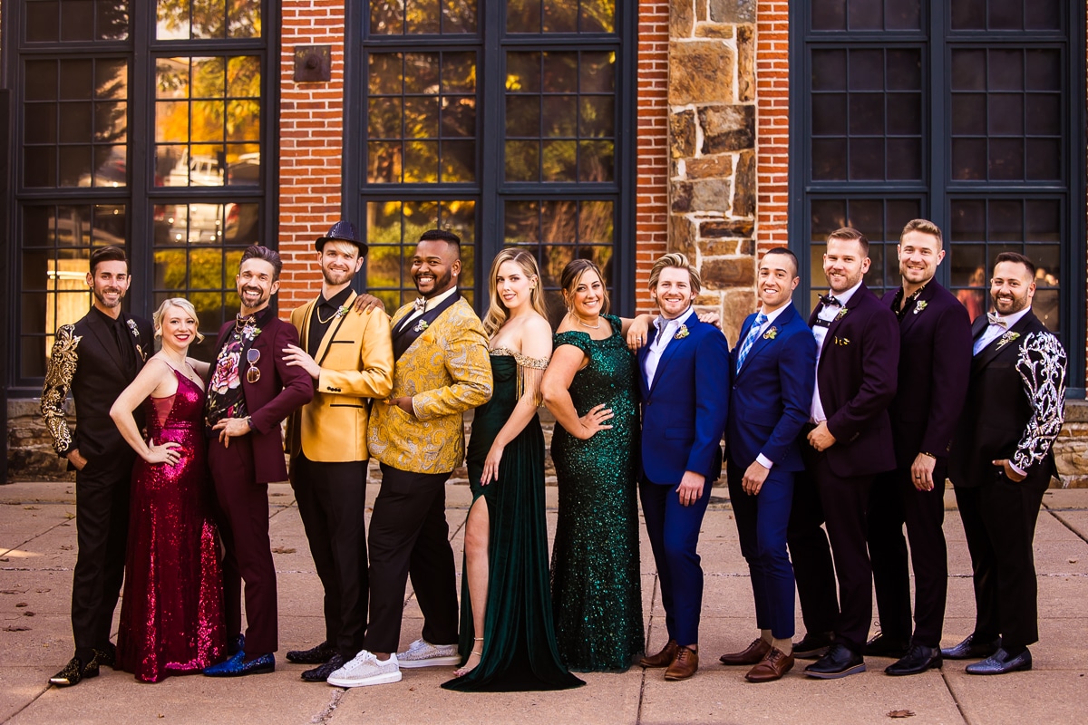 Colorful and vibrant image of the grooms and their rainbow wedding party dressed in jewel tone attire for this Phoenixville Foundry wedding