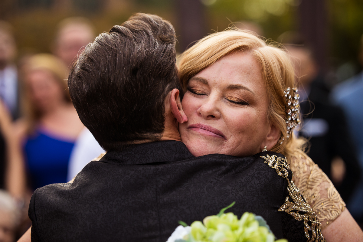 philly wedding photographer, lisa rhinehart, captures an image of the groom hugging his mom during their wedding ceremony at the Phoenixville, foundry in Philly pa 