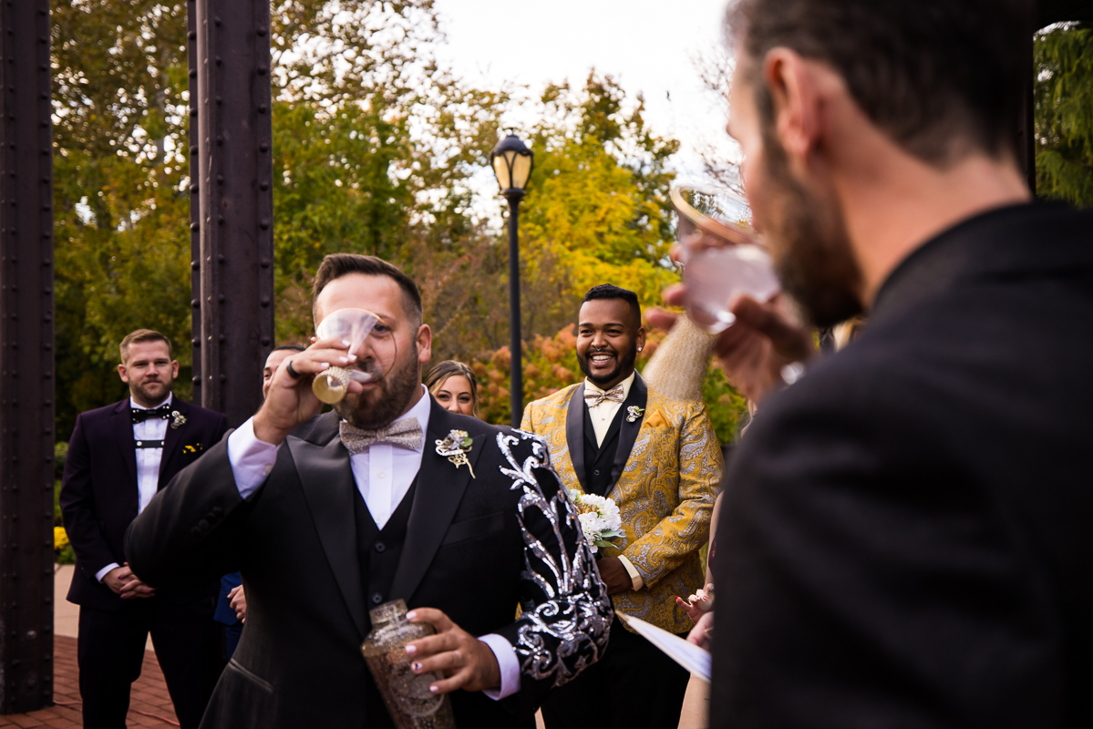 LGBT Wedding Photographer, lisa rhinehart, captures this couple as they share a drink during their wedding ceremony at the Phoenixville foundry in Philly pa 