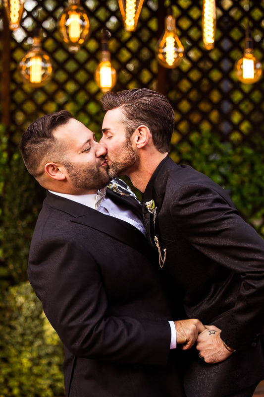 LGBT Wedding Photographer, LIsa Rhinehart, captures this gay couple first kiss during their wedding ceremony at the phoenxiville foundry during their wedding ceremony 