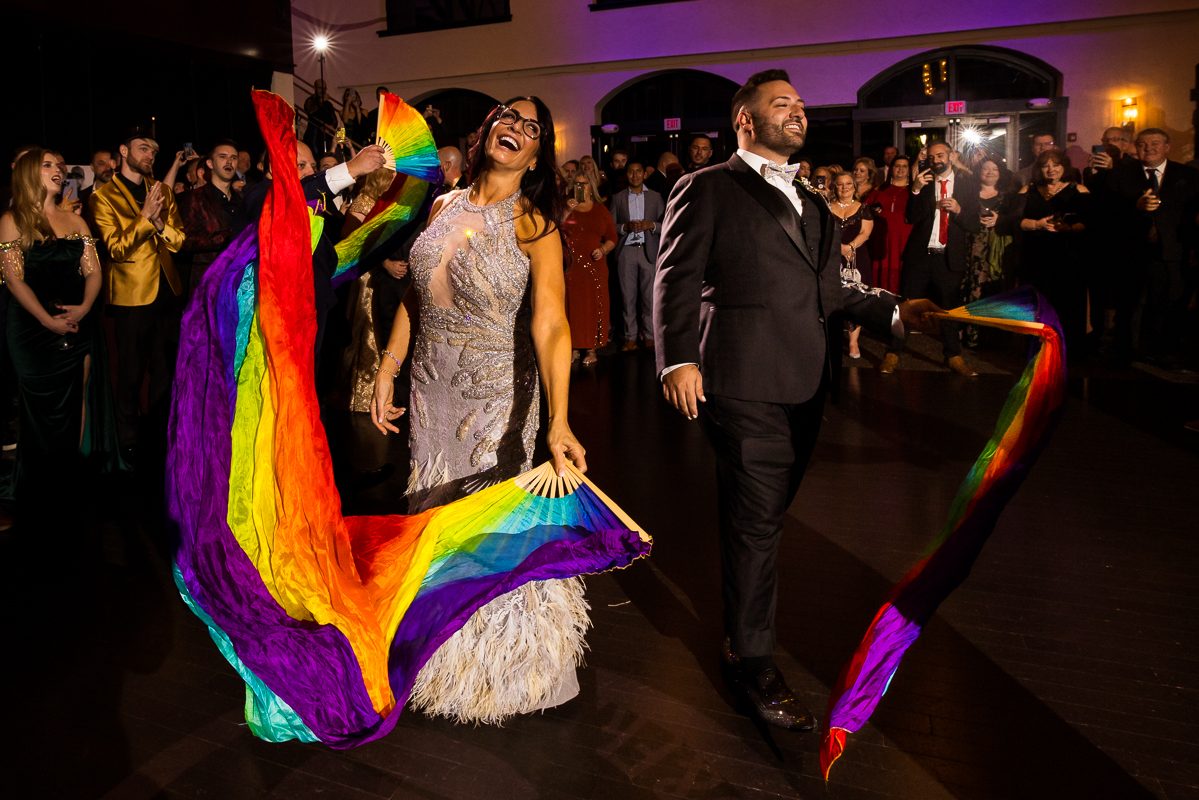 image of the groom and his mom dancing with giant rainbow flags during their mom/son dance at this wedding reception in Philadelphia 