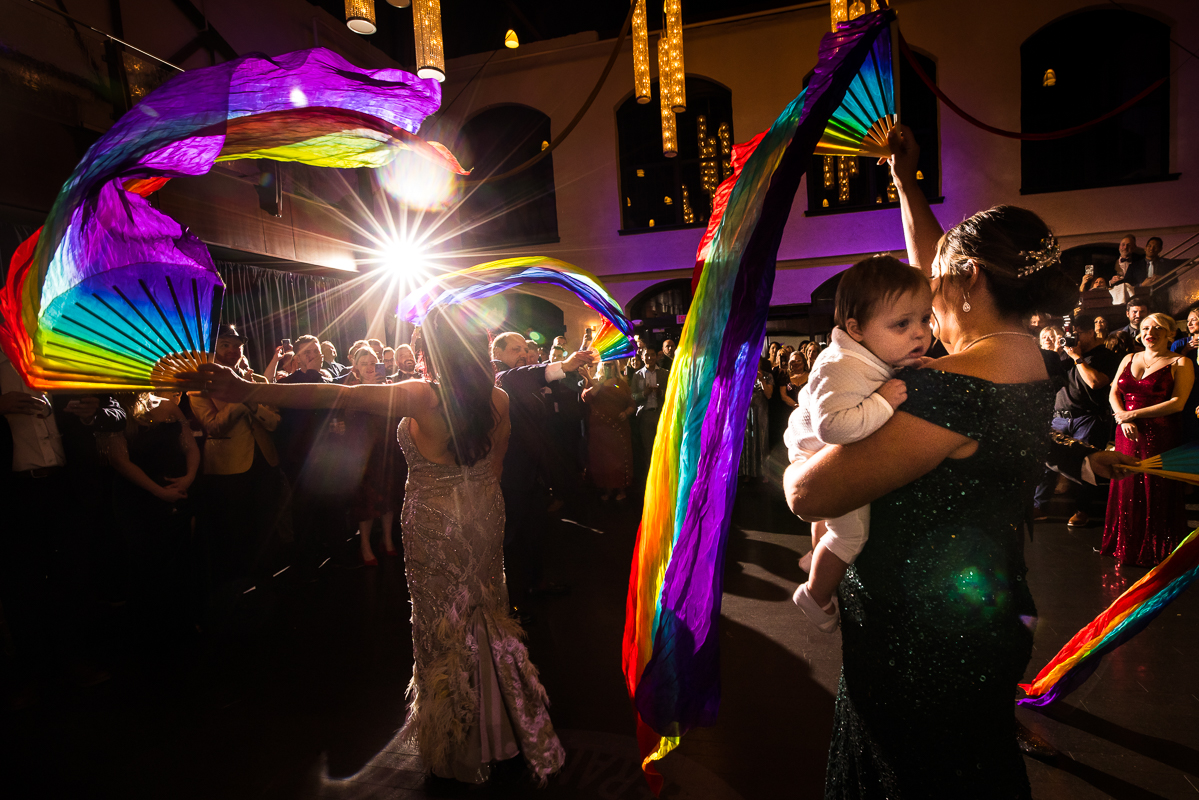 unique, vibrant, colorful, creative image of family and friends dancing with the giant rainbow flags during the wedding reception at the Phoenixville foundry in Philadelphia, pa 