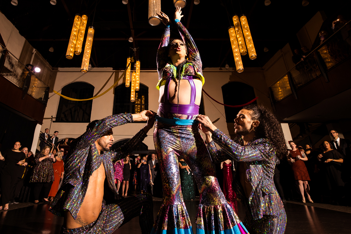 LGBT Wedding Photographer, Lisa Rhinehart, captures burlesque dancers dancing during this gay wedding reception at the Phoenixville foundry in Philadelphia, pa 