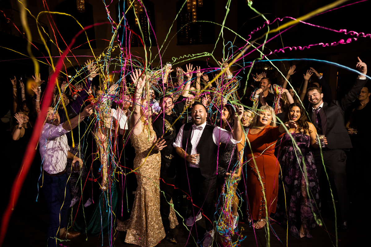 LGBT Wedding Photographer, Lisa Rhinehart, captures a colorful, vibrant, creative end of the night shot with the entire group as the streamers are flying around everyone 
