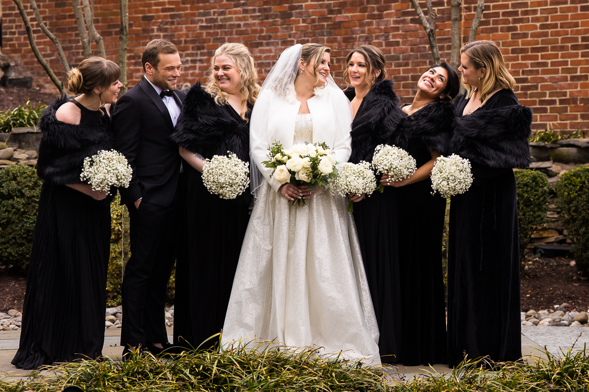 Traditional, candid image of the bride with her bridal party as they all laugh and smile at one another outside of the ritz-carlton hotel in dc before their wedding ceremony 
