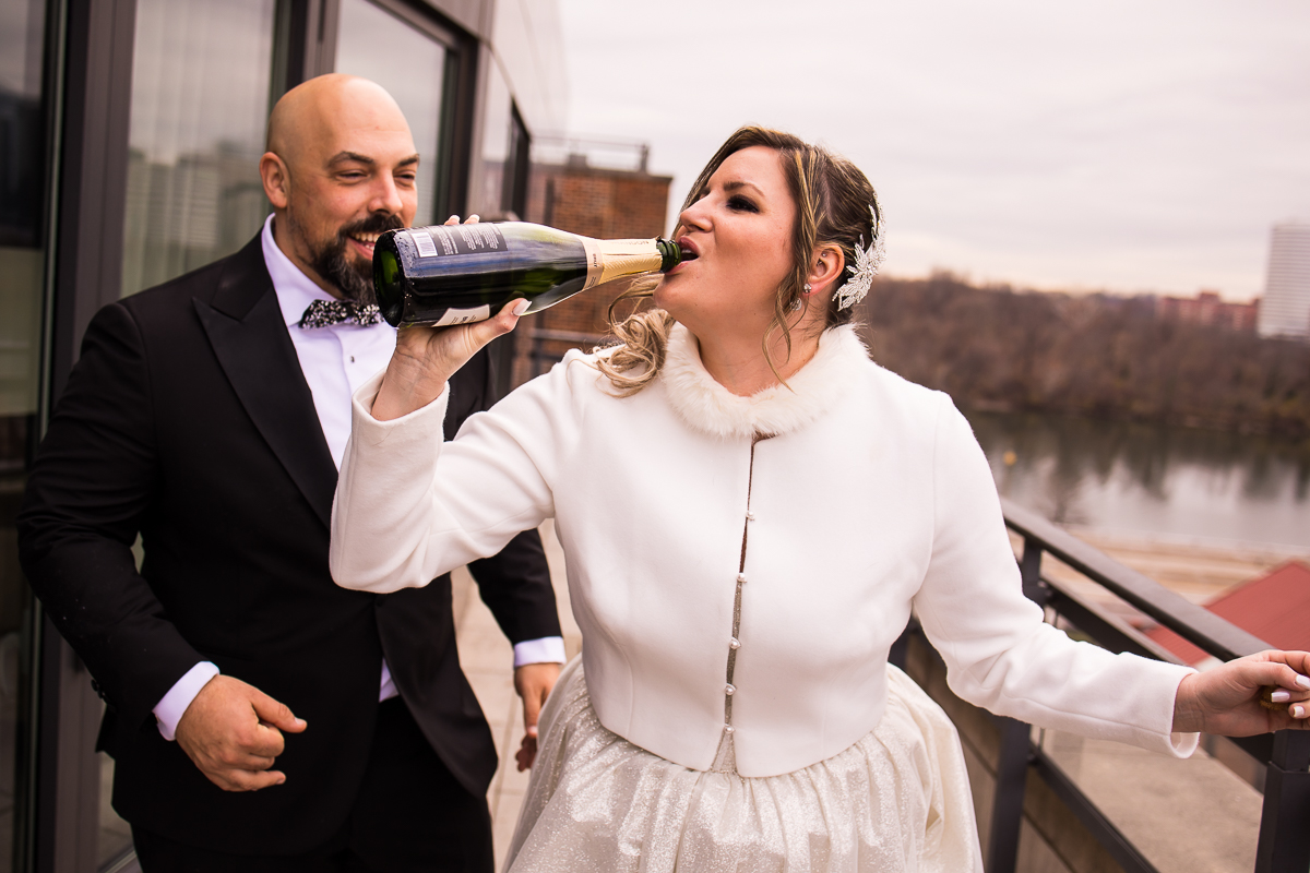 candid image of the bride and the groom as they pop the champagne and drink it on the balcony of the hotel in Washington dc
