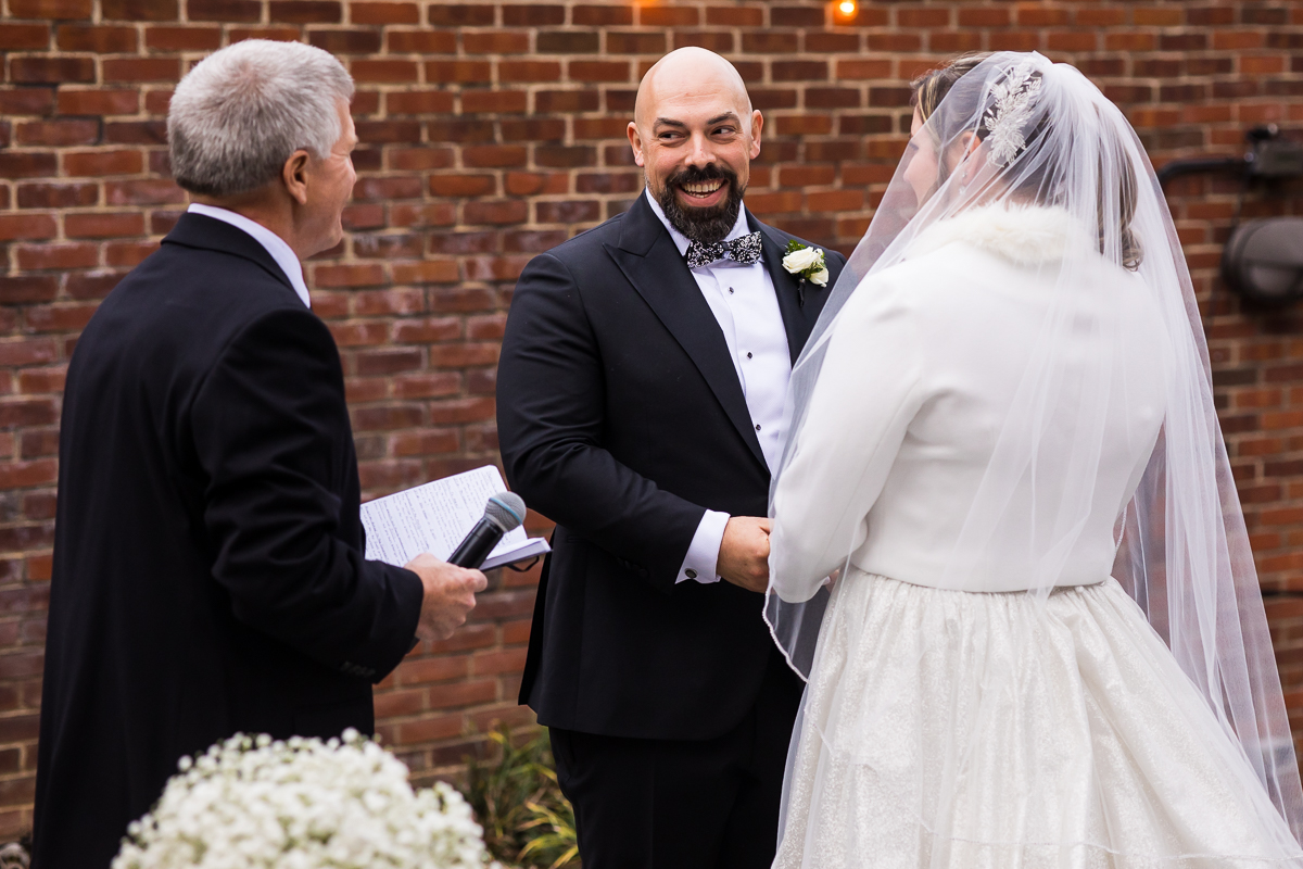 Image of the bride and groom holding one anothers hands as they stand at the end of the aisle during the Georgetown wedding ceremony 