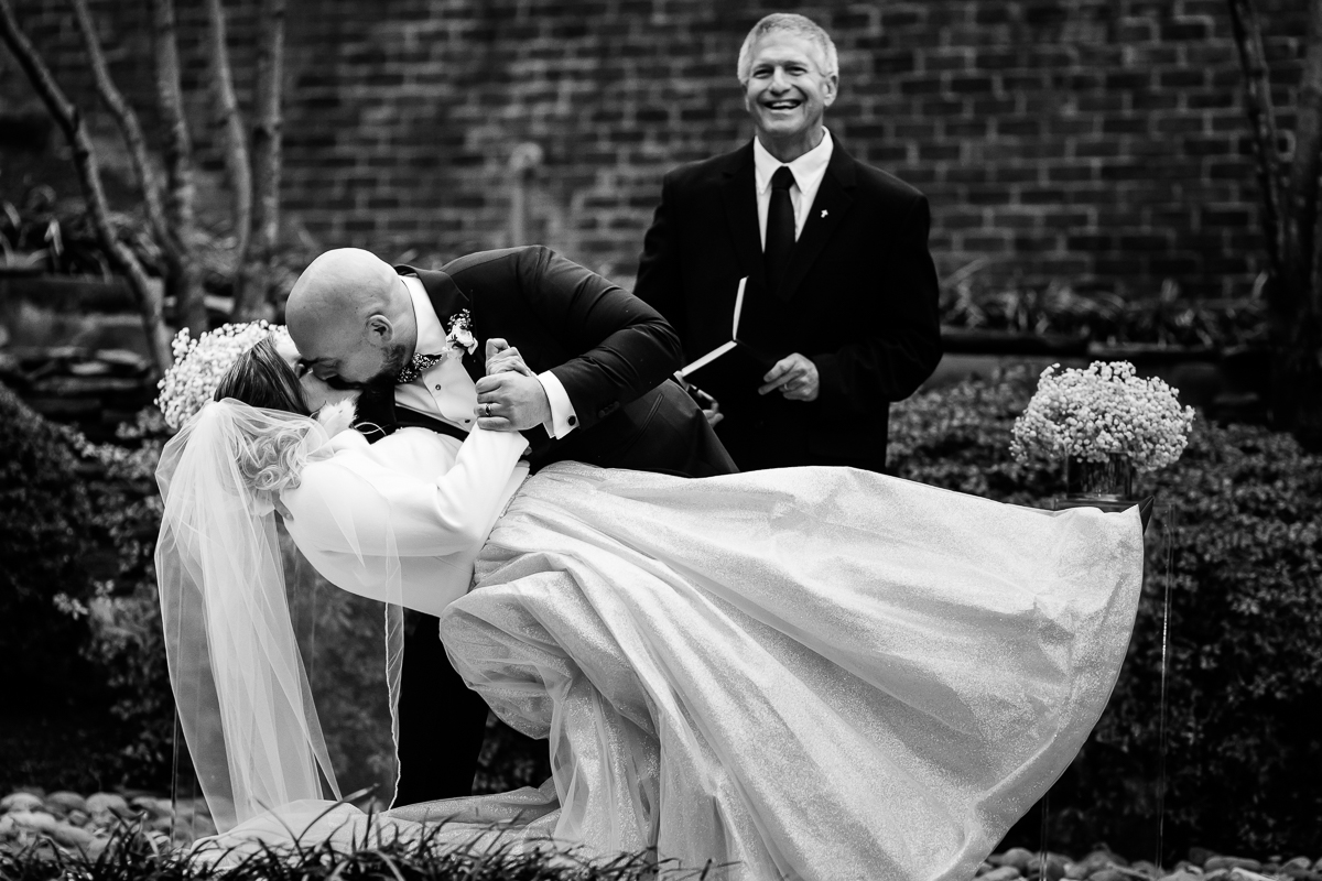 Ritz Carlton Georgetown Wedding photographers, rhinehart photography, captures this classic, elegant, timeless Black and white image of the bride and groom sharing their first kiss as they do a dip backwards at the end of their wedding ceremony 