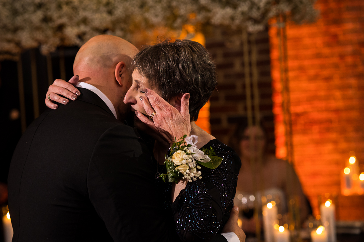 image of the groom dancing with his mom as she wipes her eyes during their mother son dance during the wedding reception at the ritz carlton 
