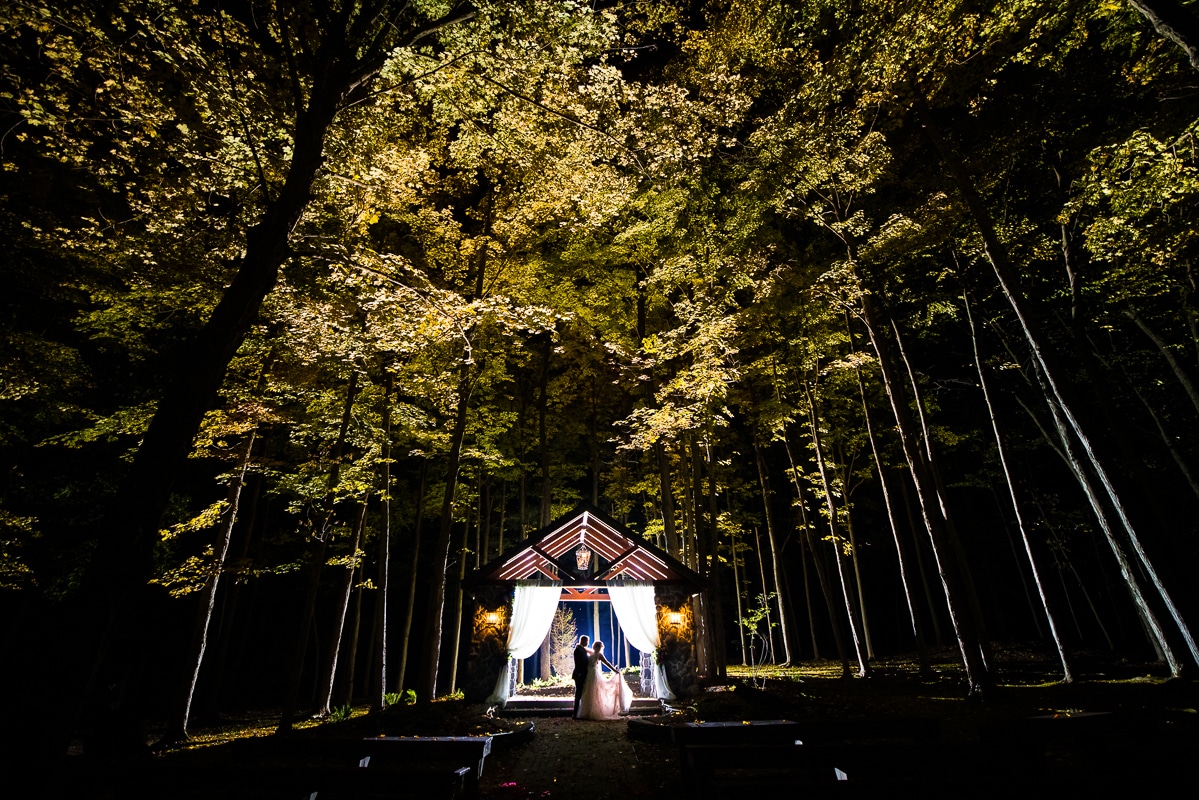 unique, creative image of the couple standing underneath the ceremony gazebo surrounded by tall trees after their stroudsmoor wedding reception