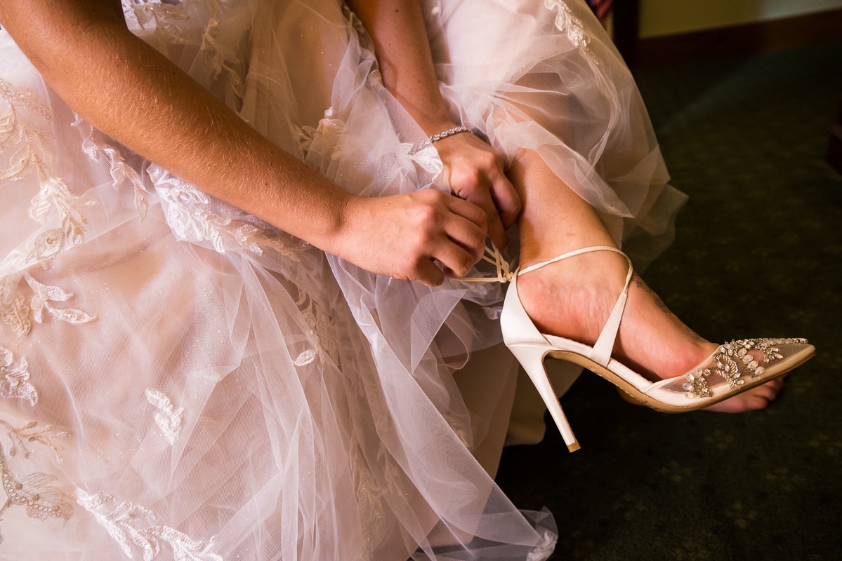 traditional image of the bride putting on her high heeled shoes before her wedding ceremony at the stroudsmoor county inn 
