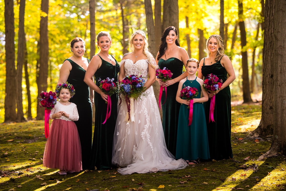 Stroudsmoor wedding photographer, lisa rhinehart, captures a traditional vibrant, colorful portrait of the bride, bridesmaids, and flower girls in their emerald green dresses and holding their colorful vibrant bouquets 