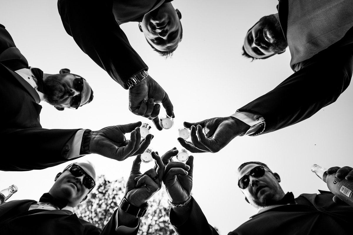 Pocono Wedding Photographer, lisa rhinehart, captures a unique and creative black and white perspective of the groom and his groomsmen drinking prior to the wedding ceremony at the stroudsmoor