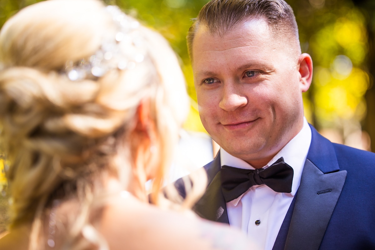 best pa wedding photographer, lisa rhinehart, captures the groom smiling at the bride during their first look at stroudsmoor woodsgate