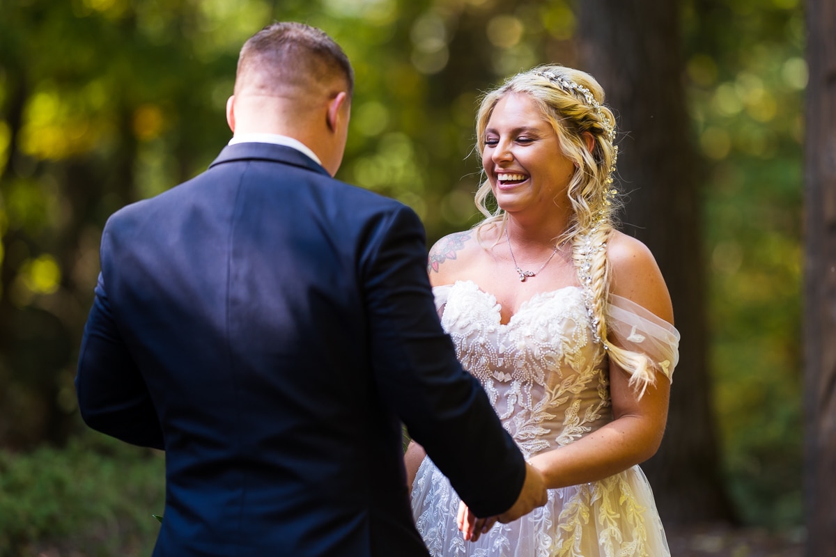 stroudsmoor wedding photographer, rhinehart photography, captures the couple during their first look laughing and smiling at one another as they hold hands surrounded by the fall leaves and trees