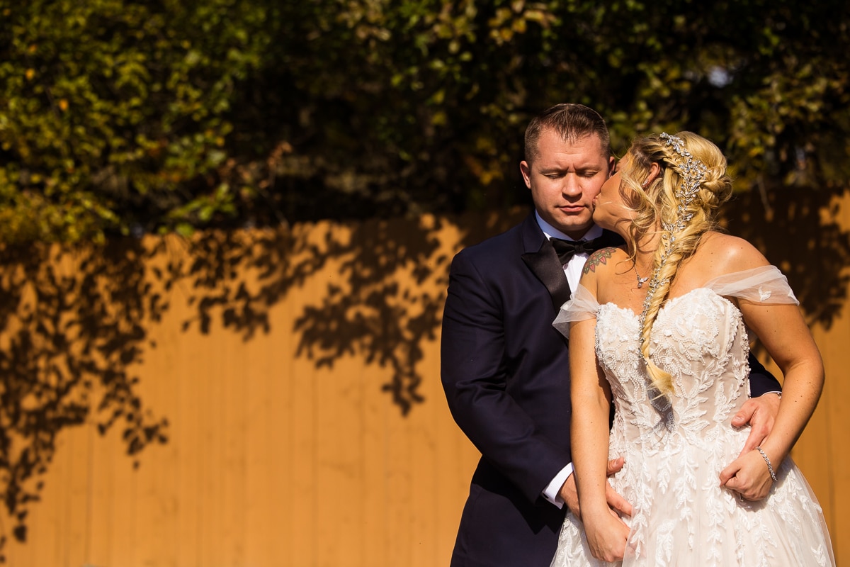 wedding photographer, rhinehart photography, captures the bride kissing the groom on his cheek during the outdoor fall wedding at the stroudsmoor