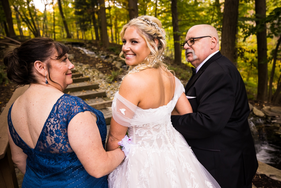 image of the bride with her parents looking back and smiling before she walks up the walkway to the wedding ceremony 