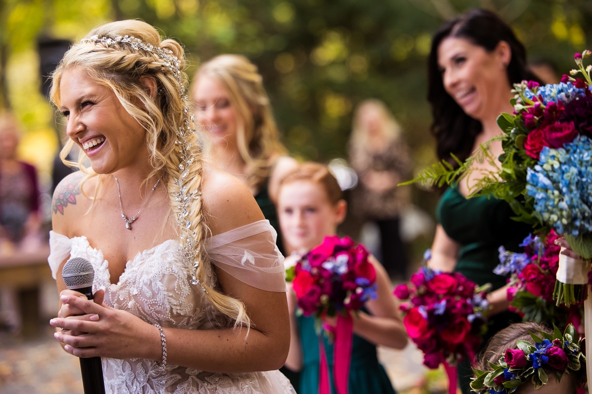 vibrant, colorful image of the bride holding a microphone as she has a huge smile on her face with her bridesmaids behind her as they hold the vibrant colorful bouquets