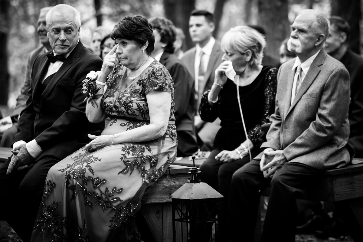 Pocono wedding photographer, rhinehart photography, captures this black and white image of parents and guests as they cry during the wedding ceremony at the stroudsmoor
