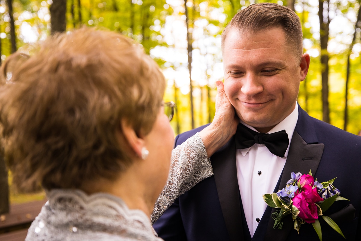 image of the groom smiling as someone puts their hand up to the side of his face after his wedding ceremony at the stroudsmoor