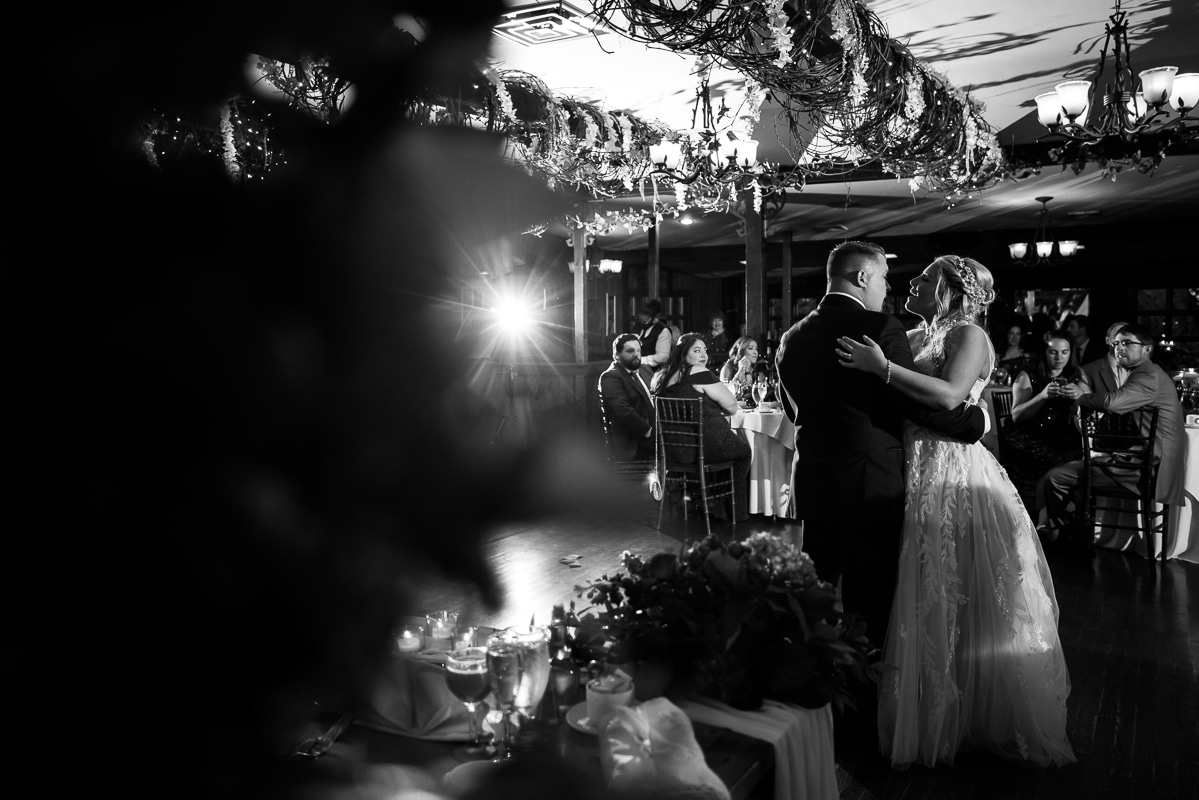 Pocono wedding photographer, lisa rhinehart, captures this black and white image of the couple as they share their first dance together inside of the stroudsmoor 