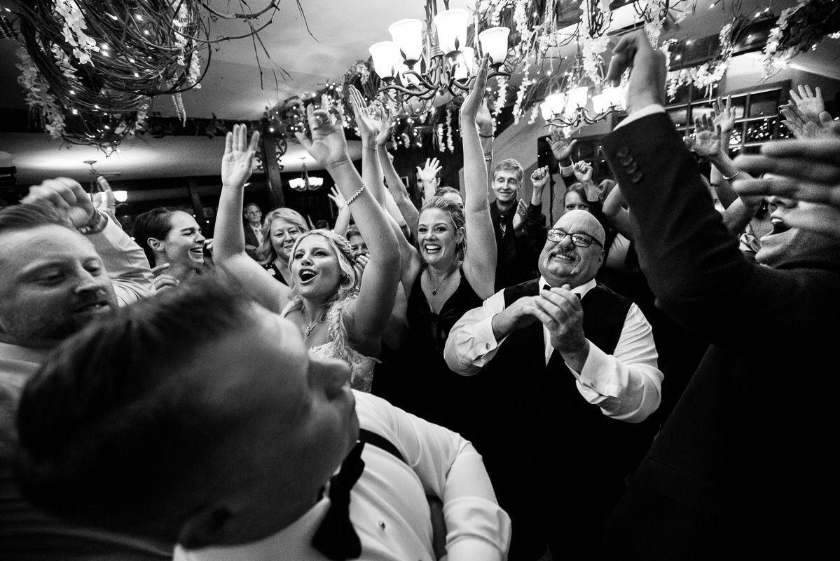 Pocono wedding photographer, lisa rhinehart, captures the couple dancing with their guests with their hands in the air during the wedding reception at the stroudsmoor as the lights and decor fill the ceiling above them 